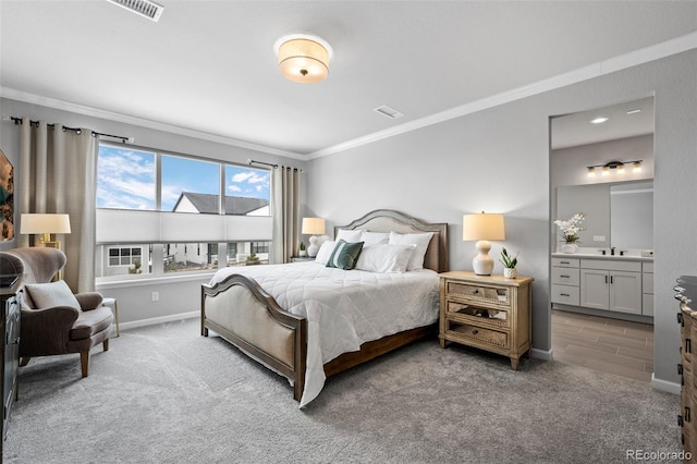 carpeted bedroom with ornamental molding, ensuite bathroom, and sink