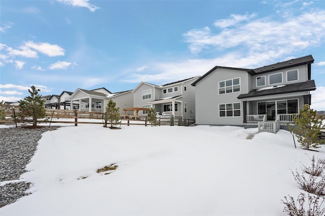 snow covered rear of property featuring covered porch