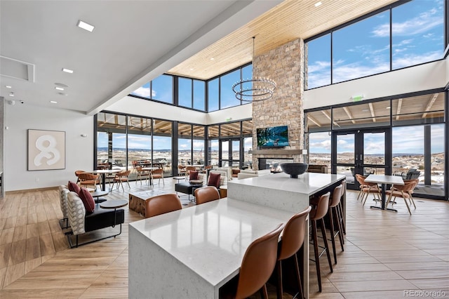 dining room with a stone fireplace, a towering ceiling, a wealth of natural light, and french doors