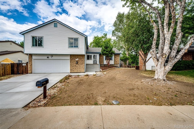 split level home with concrete driveway, an attached garage, fence, and brick siding