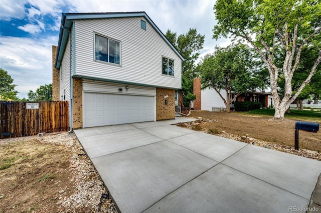 view of front facade featuring brick siding, concrete driveway, an attached garage, and fence