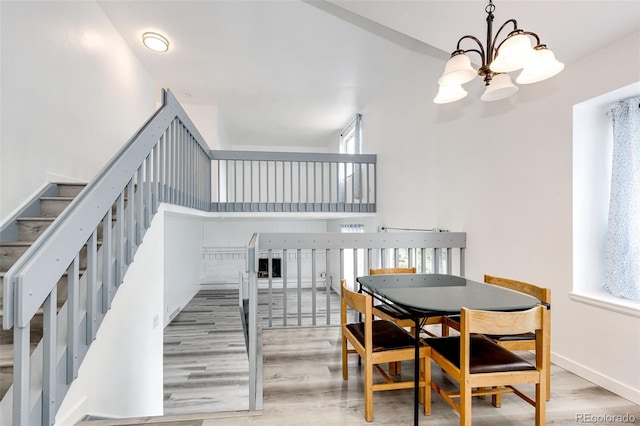 dining room featuring baseboards, wood finished floors, stairs, a towering ceiling, and an inviting chandelier