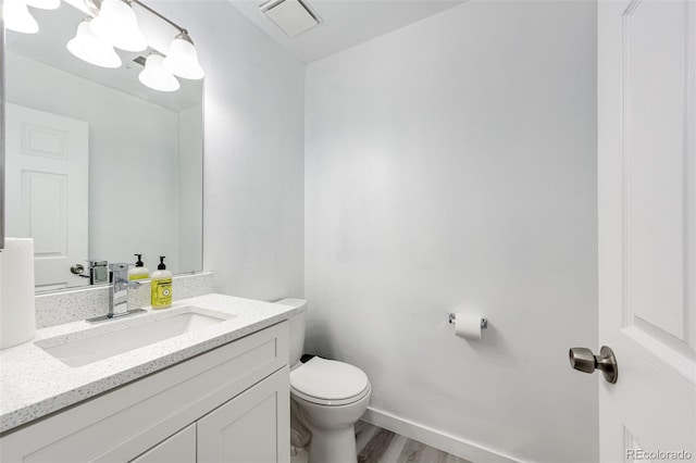 bathroom with visible vents, toilet, wood finished floors, baseboards, and vanity