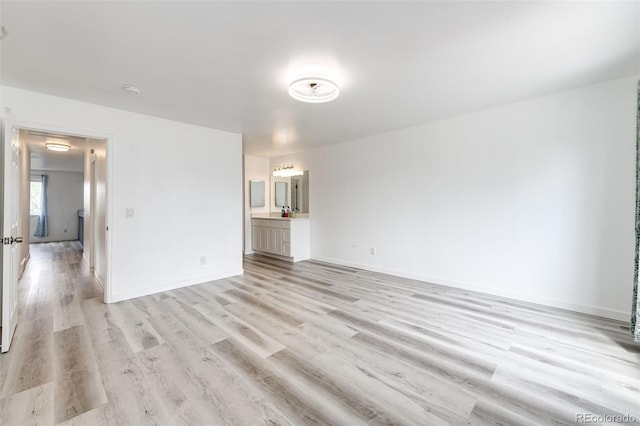 unfurnished living room with light wood-style flooring and baseboards