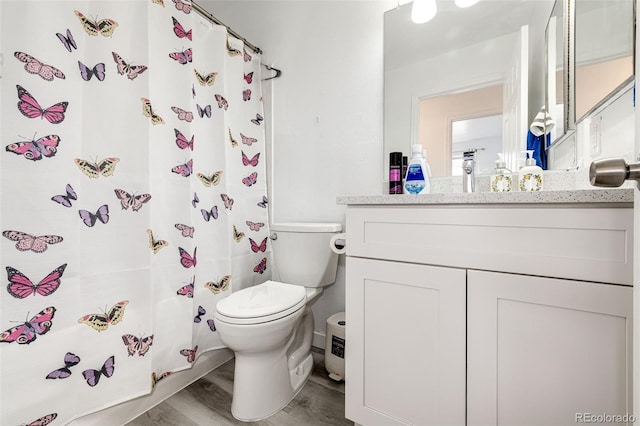 bathroom with vanity, a shower with shower curtain, toilet, and wood finished floors