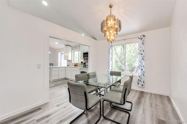 dining space with a chandelier, baseboards, and light wood-style floors