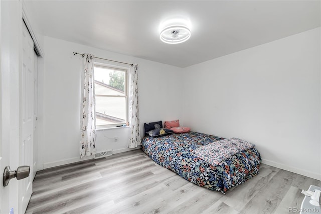 bedroom with visible vents, baseboards, a closet, and wood finished floors