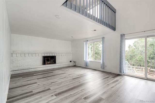 unfurnished living room featuring a fireplace, wood finished floors, baseboards, and a towering ceiling