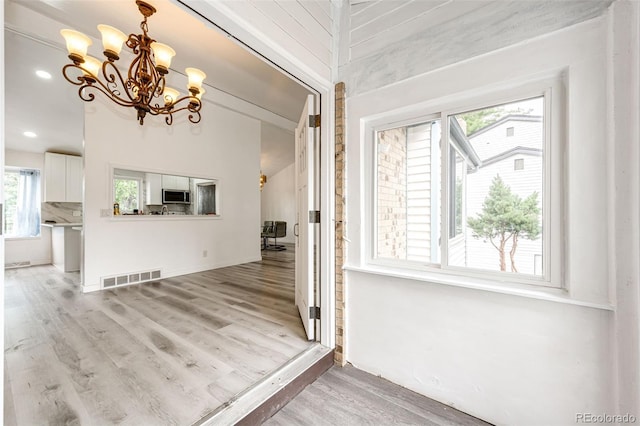 interior space with visible vents, an inviting chandelier, and wood finished floors