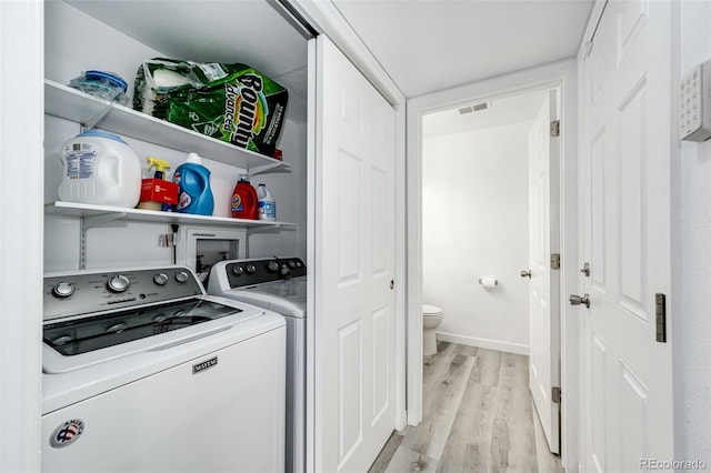 laundry area with visible vents, baseboards, laundry area, light wood-style flooring, and washing machine and dryer