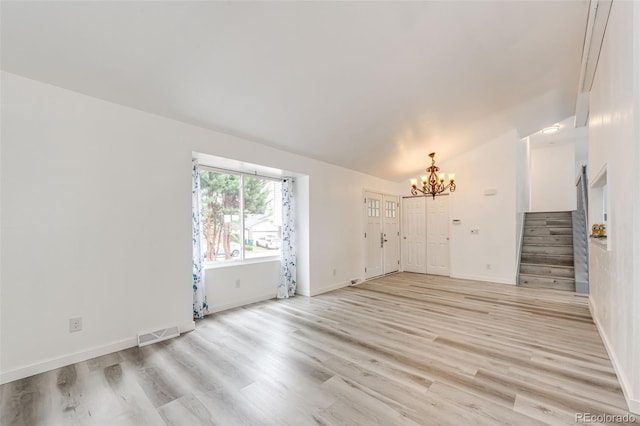 unfurnished room with visible vents, light wood-style flooring, a chandelier, stairs, and vaulted ceiling