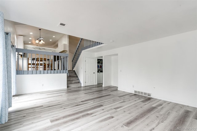 unfurnished living room with recessed lighting, visible vents, wood finished floors, and stairway