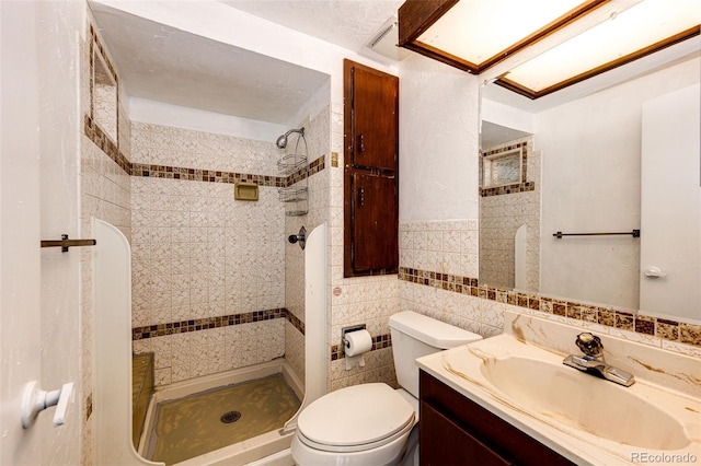 bathroom with toilet, vanity, tile walls, and a shower stall