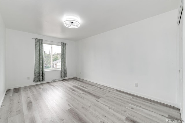 spare room featuring visible vents, baseboards, and light wood-style floors