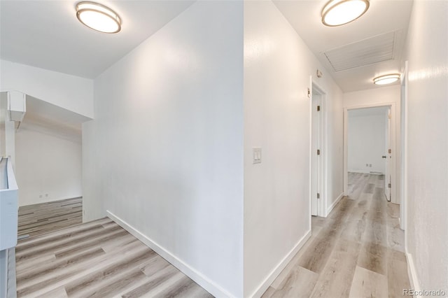 corridor with baseboards and light wood-style floors