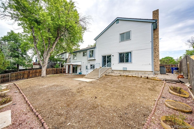 rear view of property featuring central air condition unit, entry steps, a chimney, and a fenced backyard