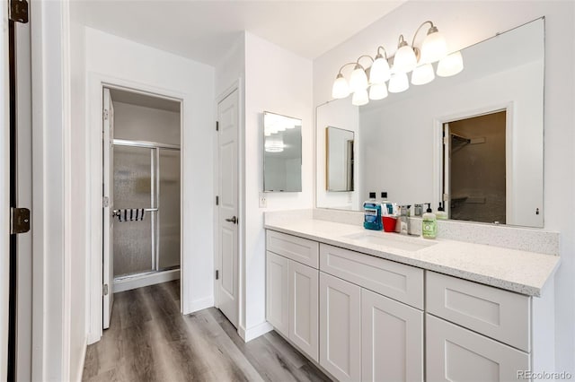 full bathroom featuring wood finished floors, a stall shower, and vanity