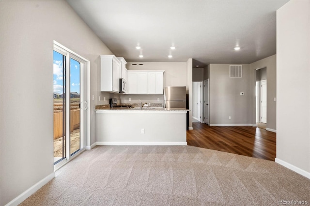 7326 Green River Ave, Frederick, CO 80530 - kitchen featuring carpet floors, appliances with stainless steel finishes, baseboards, white cabinetry, and a peninsula