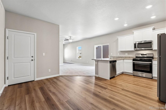 7326 Green River Ave, Frederick, CO 80530 - kitchen with stainless steel appliances, open floor plan, white cabinets, a peninsula, and recessed lighting