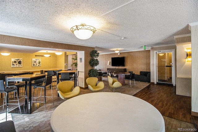 dining area featuring hardwood / wood-style floors, a textured ceiling, and ornamental molding