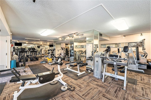 workout area featuring rail lighting and a textured ceiling