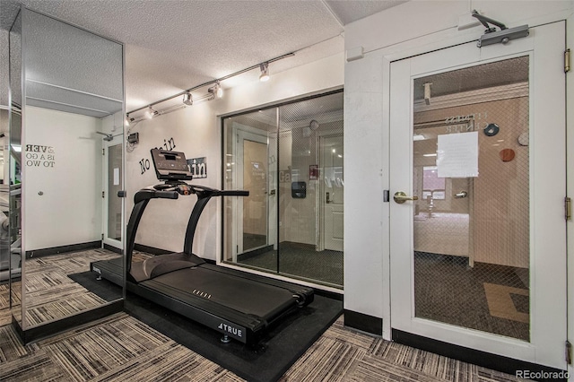 exercise area with rail lighting and a textured ceiling