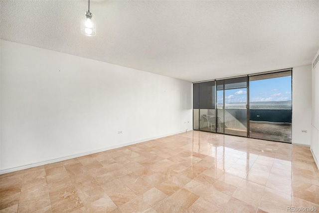 unfurnished room featuring a textured ceiling and a wall of windows