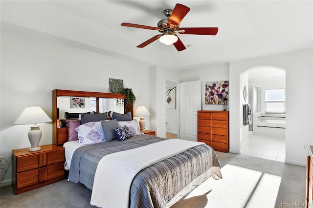 bedroom featuring arched walkways, light carpet, ensuite bathroom, and ceiling fan