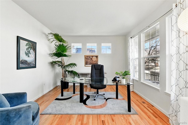 home office with baseboards and wood finished floors