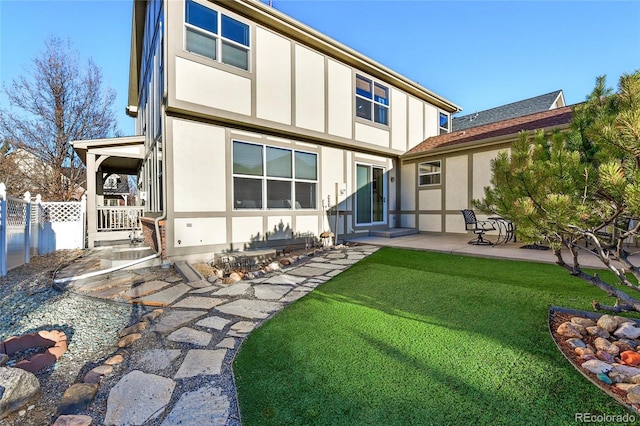 back of house featuring a patio area, fence, a lawn, and stucco siding