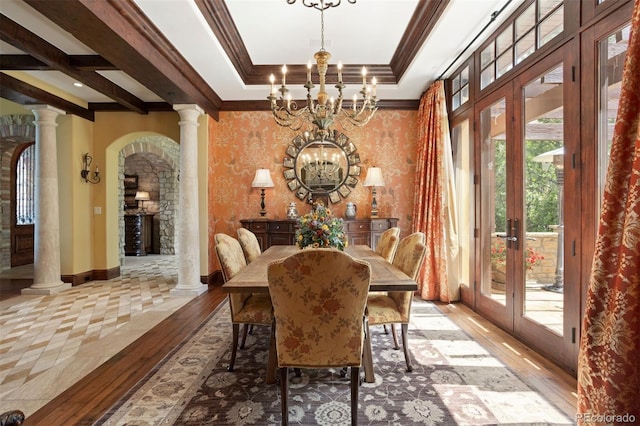 dining room featuring french doors, an inviting chandelier, crown molding, ornate columns, and light wood-type flooring