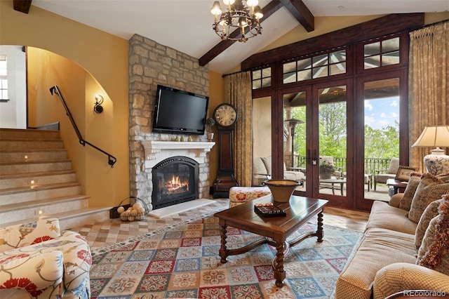 living room featuring french doors, light wood-type flooring, a notable chandelier, vaulted ceiling with beams, and a stone fireplace