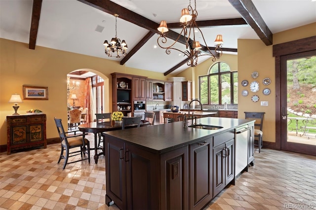 kitchen with sink, hanging light fixtures, dark brown cabinets, and a center island with sink