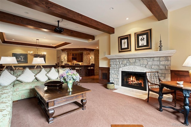 living room featuring carpet flooring, a stone fireplace, and a chandelier