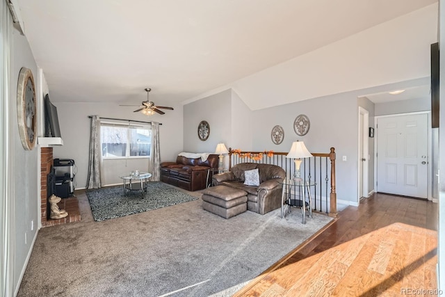 living room with hardwood / wood-style floors, vaulted ceiling, ceiling fan, and a wood stove