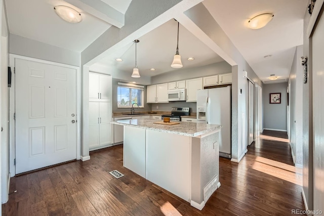 kitchen with white appliances, dark hardwood / wood-style floors, light stone countertops, and a kitchen island