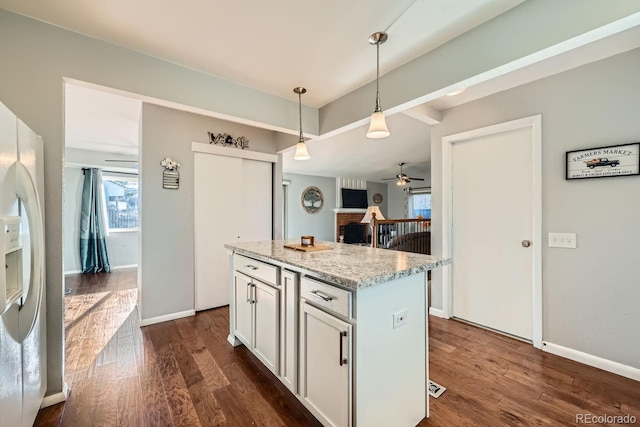 kitchen with hanging light fixtures, light stone counters, dark hardwood / wood-style floors, a fireplace, and a kitchen island