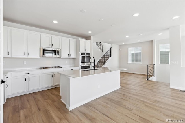 kitchen with white cabinets, a kitchen island with sink, and appliances with stainless steel finishes