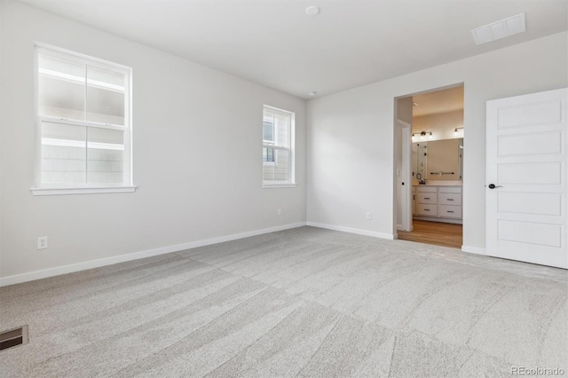 unfurnished bedroom featuring carpet floors and ensuite bath