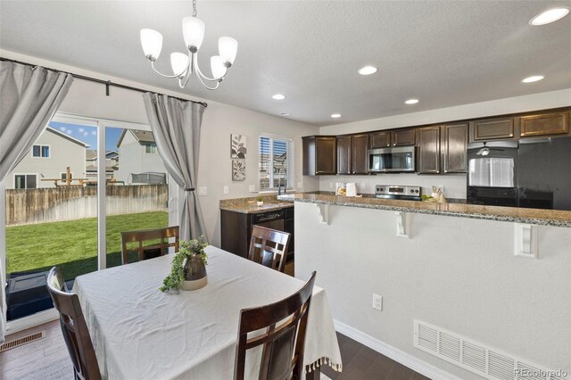 kitchen featuring light stone countertops, dark hardwood / wood-style flooring, hanging light fixtures, and appliances with stainless steel finishes