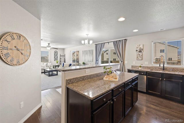 kitchen featuring dishwasher, sink, light stone counters, dark hardwood / wood-style floors, and a textured ceiling