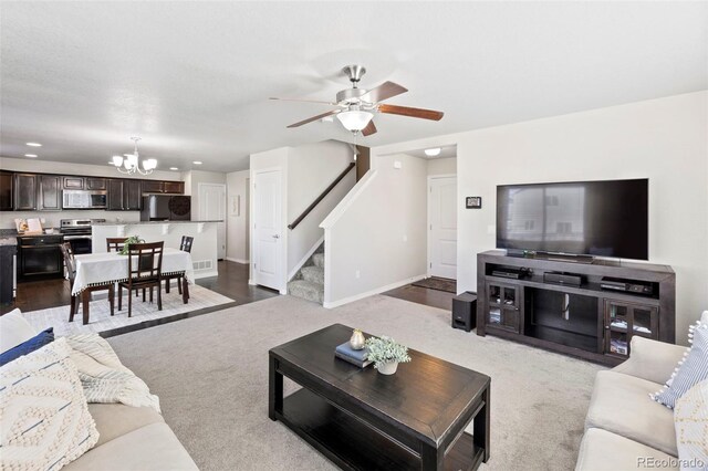 living room with ceiling fan with notable chandelier and light hardwood / wood-style flooring