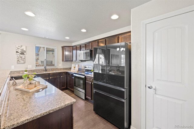 kitchen featuring sink, dark hardwood / wood-style floors, light stone counters, dark brown cabinetry, and stainless steel appliances