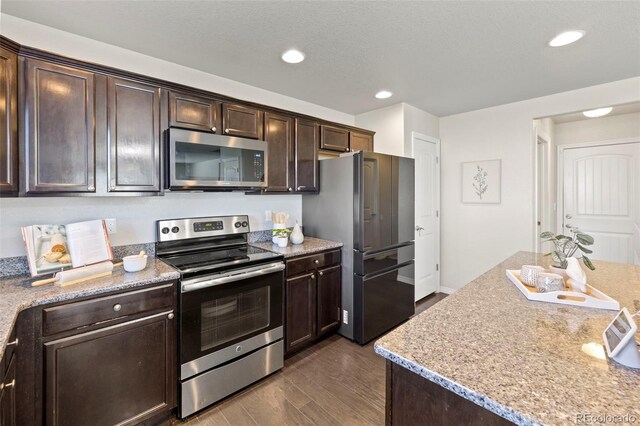 kitchen featuring appliances with stainless steel finishes, dark brown cabinetry, and dark wood-type flooring