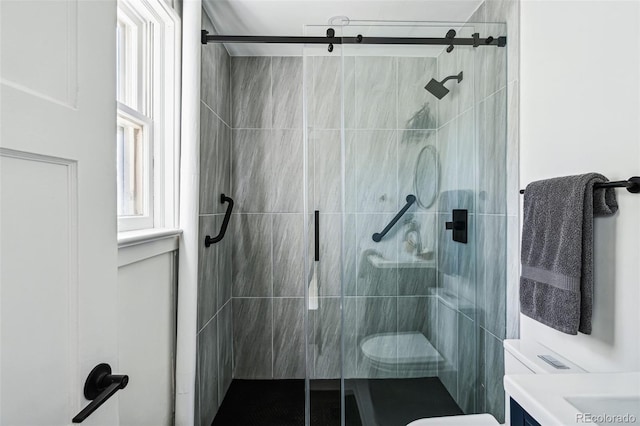 bathroom with a shower with door, vanity, and toilet