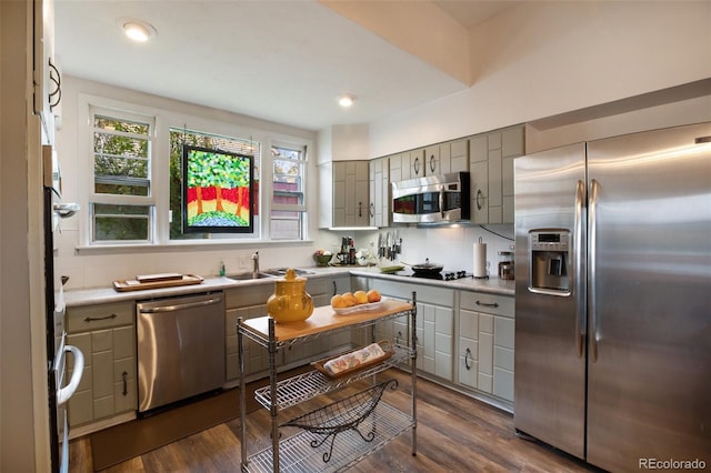 kitchen featuring sink, dark hardwood / wood-style flooring, backsplash, gray cabinets, and appliances with stainless steel finishes