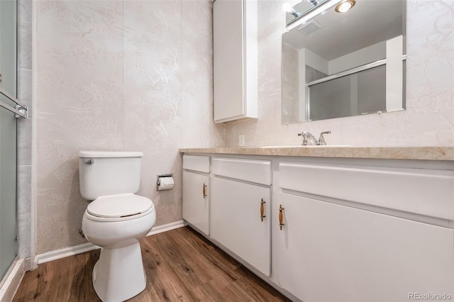 bathroom with vanity, hardwood / wood-style floors, a shower with door, and toilet