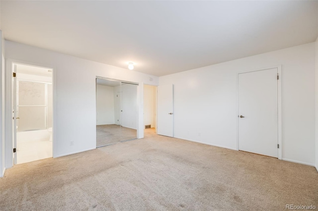 unfurnished bedroom featuring connected bathroom, light colored carpet, and a closet