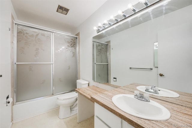 full bathroom featuring vanity, tile patterned flooring, shower / bath combination with glass door, and toilet