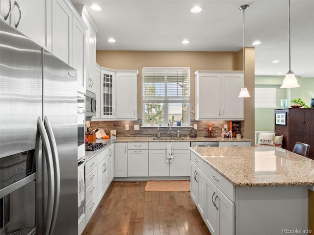 kitchen featuring stainless steel appliances, a sink, light wood finished floors, white cabinetry, and recessed lighting